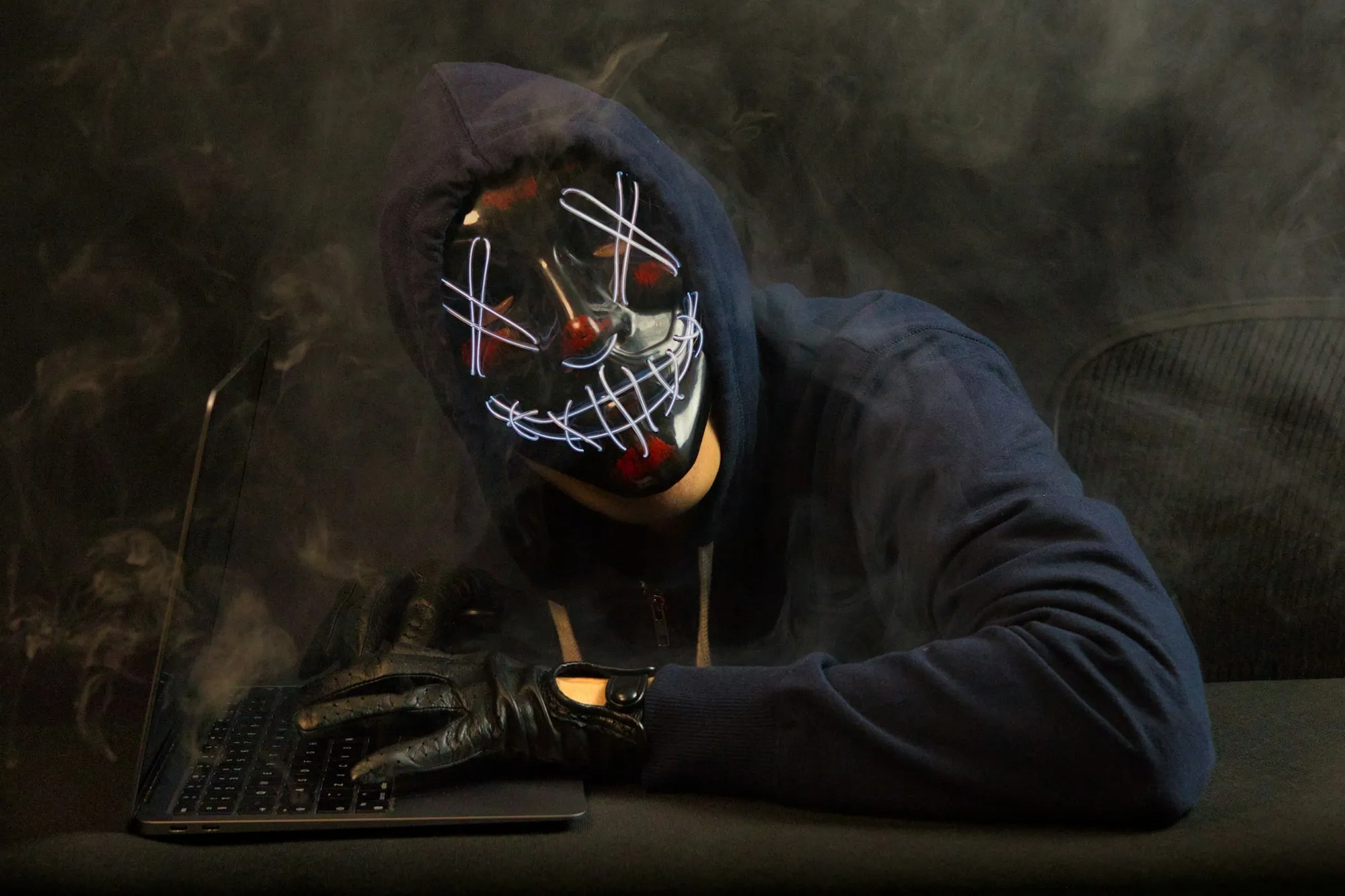 A hacker with a mask on looking intimidating towards the screen