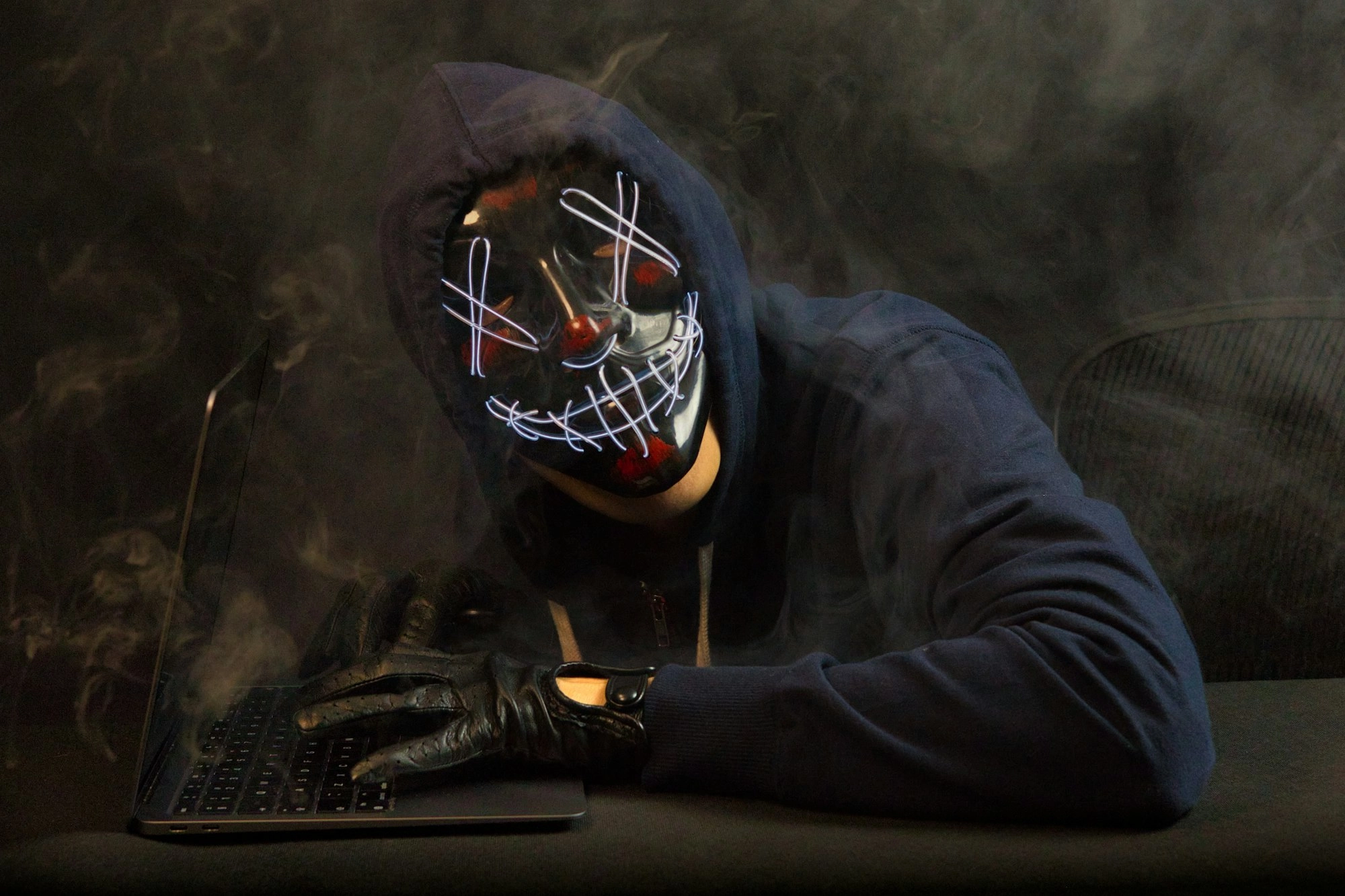 A hacker with a mask on looking intimidating towards the screen