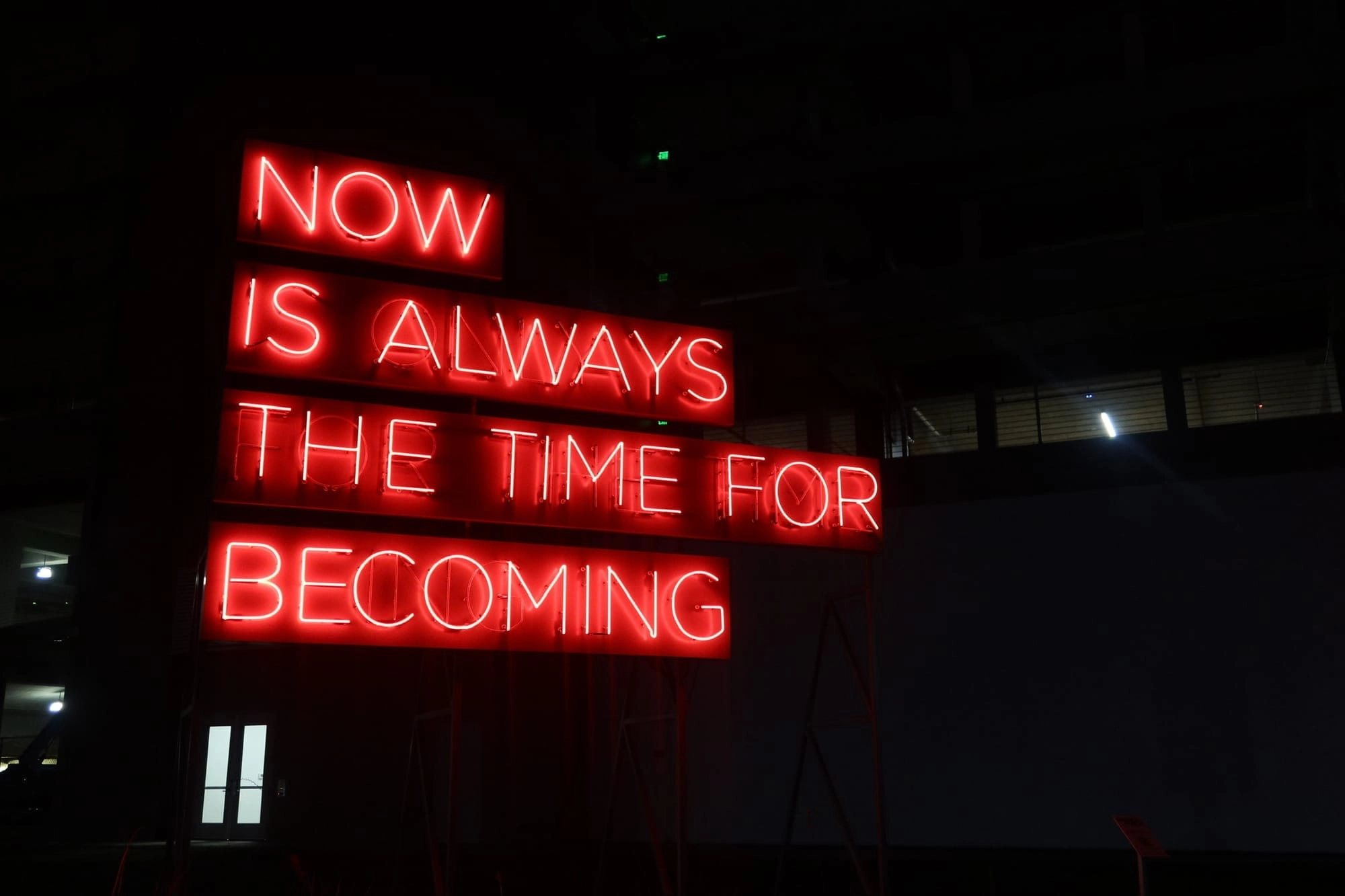 A neon sign with the words 'Now is the time for becoming' located in downtown Dallas, Texas