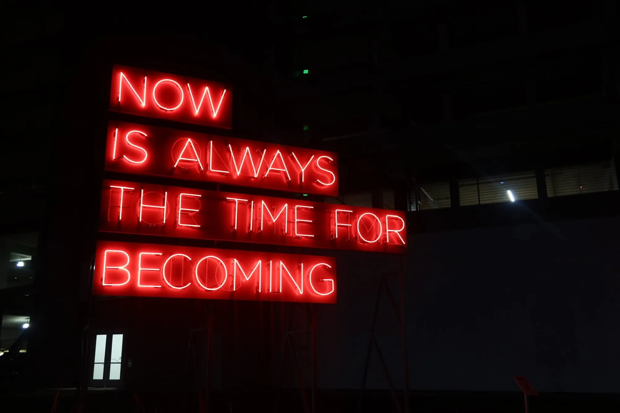 A neon sign with the words 'Now is the time for becoming' located in downtown Dallas, Texas