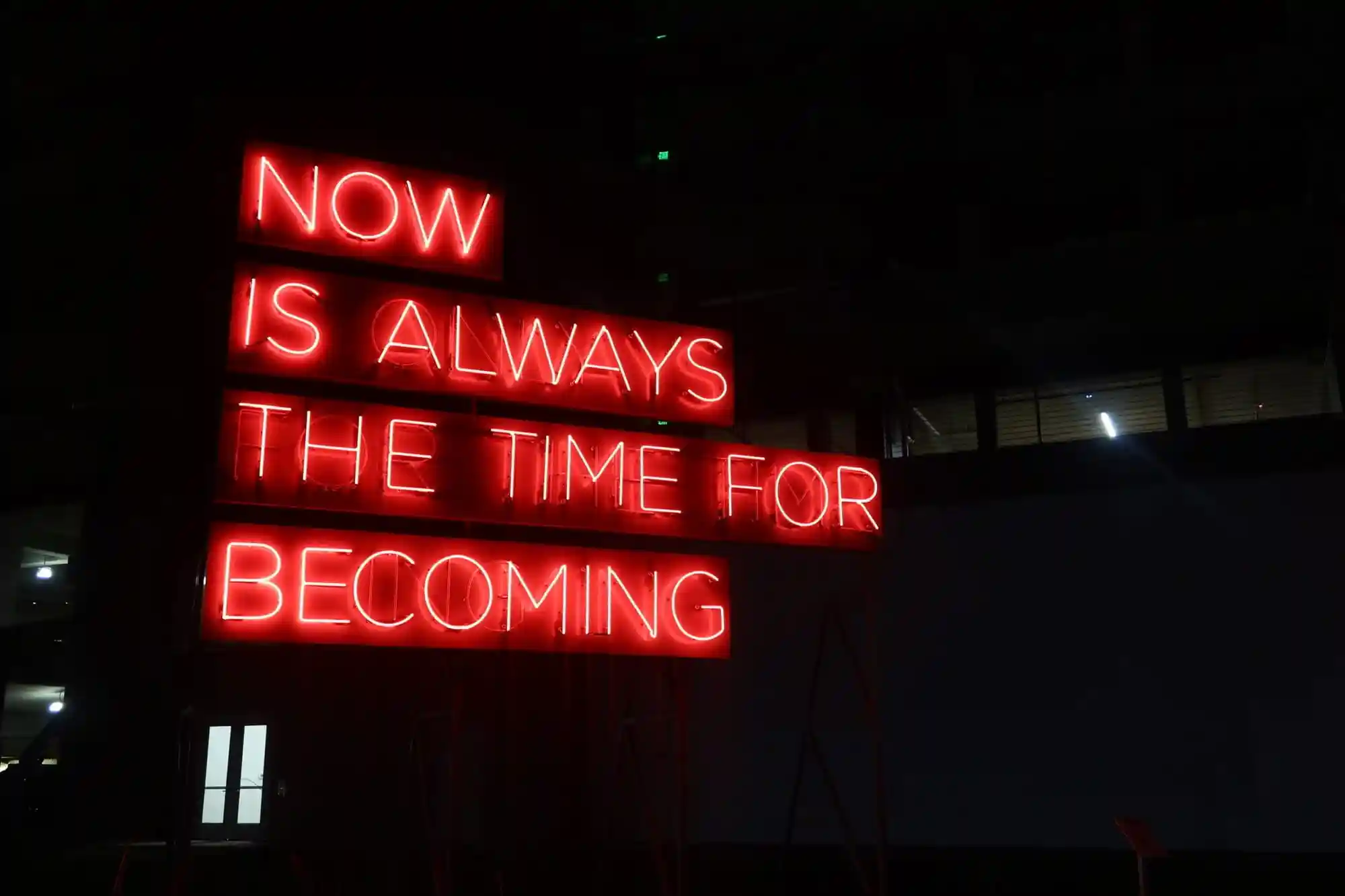 A neon sign with the words 'Now is the time for becoming' located in downtown Dallas, Texas